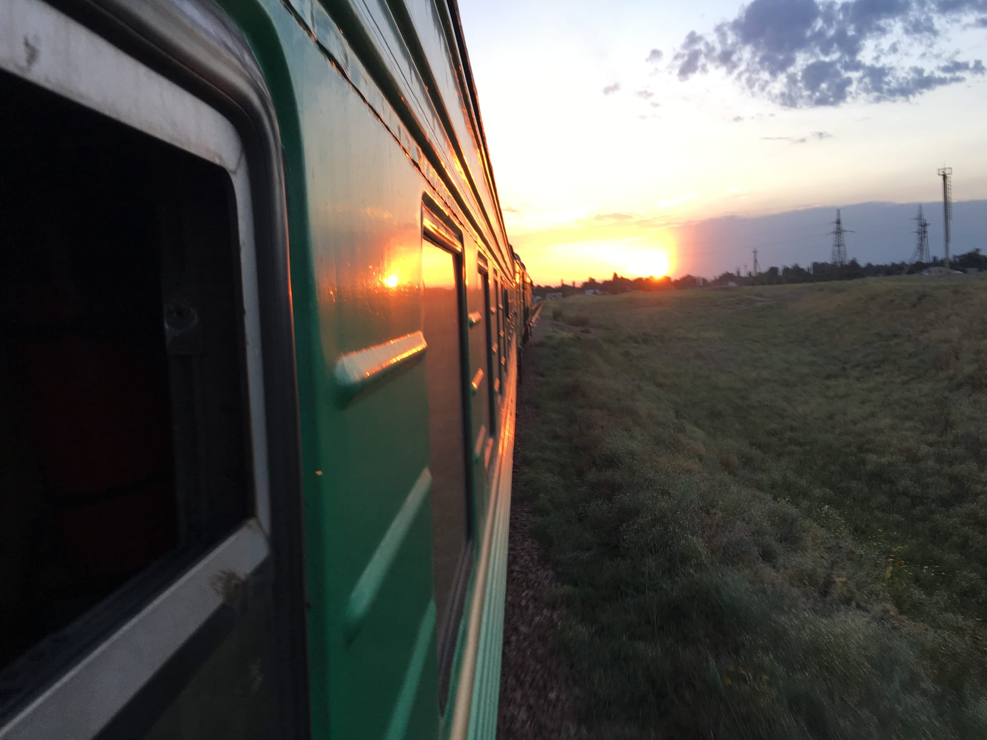 Sun setting over fields, out of the window of a train in Kyrgyzstan